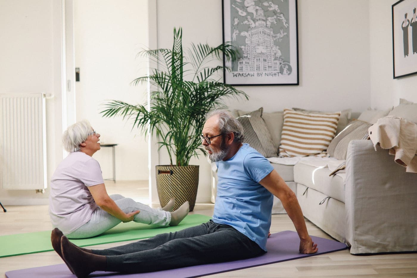 An older woman exercising at home in a living room lit by daylight