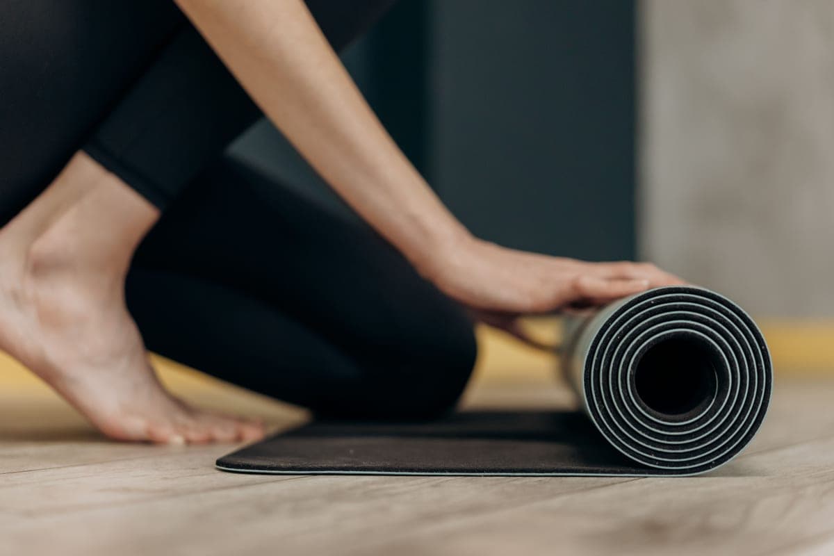 A rolled exercise mat on the floor of a bright, uncluttered room