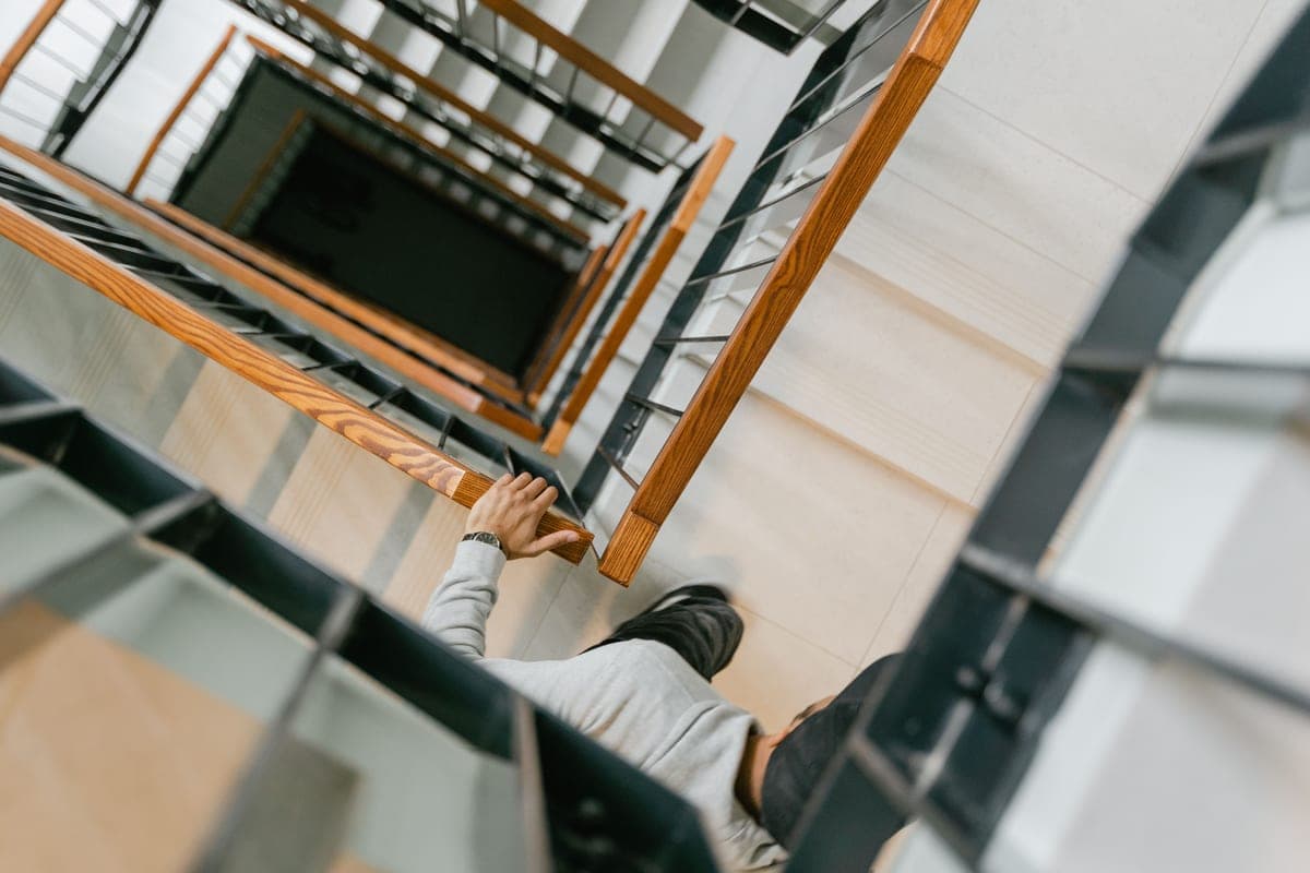 An older person's hand resting on a stair handrail for support