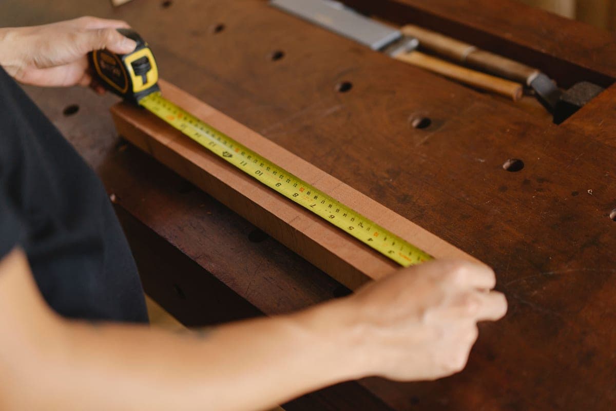 A tape measure and ruler laid out on a wooden workbench